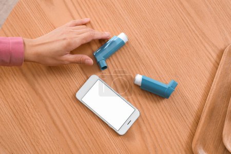 Téléchargez les photos : Jeune femme avec inhalateurs d'asthme et téléphone portable sur la table, vue du dessus - en image libre de droit