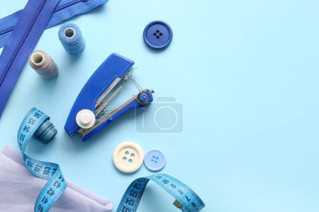 Foto de Máquina de coser manual con diferentes suministros sobre fondo azul - Imagen libre de derechos
