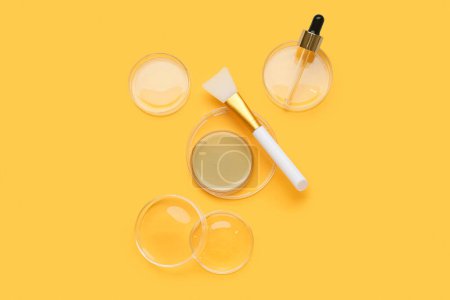 Photo for Petri dishes with sample, pipette, brush and jar of cosmetic product on yellow background - Royalty Free Image