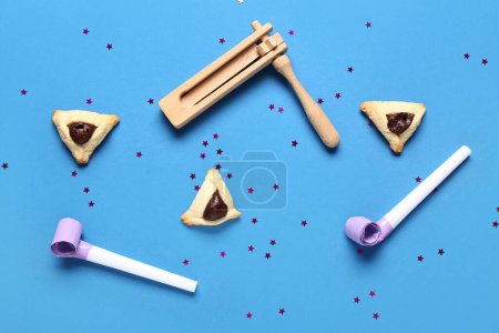 Composition with Hamantaschen cookies, rattle and party whistles for Purim celebration on color background