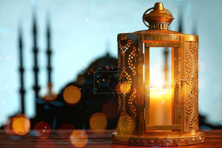 Arabic lantern with burning candle on table against blurred background