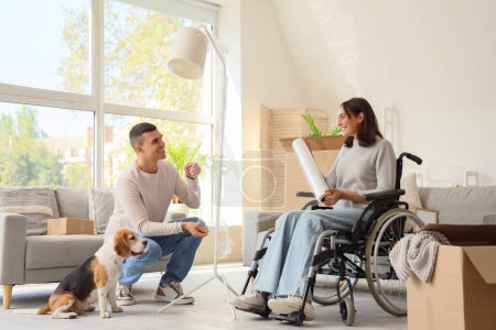 Téléchargez les photos : Jeune homme et sa femme en fauteuil roulant avec lampe d'emballage pour chien Beagle le jour du déménagement - en image libre de droit