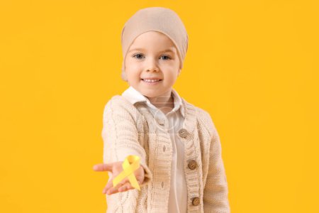 Téléchargez les photos : Petite fille après chimiothérapie avec ruban sur fond jaune. Concept de sensibilisation au cancer chez l'enfant - en image libre de droit