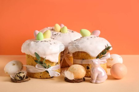 Komposition mit leckeren Osterkuchen, Porzellanhasen und bemalten Eiern auf farbigem Hintergrund