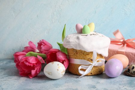Composición con deliciosa tarta de Pascua decorada, flores y huevos pintados sobre fondo de color