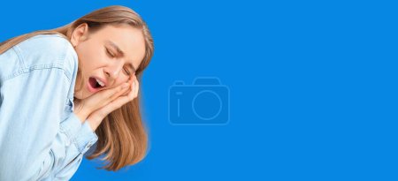 Junge Frau mit Zahnschmerzen auf blauem Hintergrund mit Platz für Text