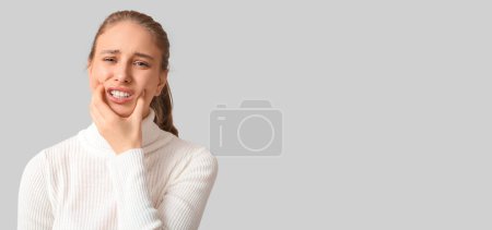 Junge Frau spürt Zahnschmerzen auf hellem Hintergrund mit Platz für Text