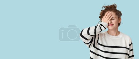 Young woman doing facepalm on light blue background with space for text