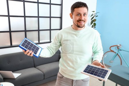 Foto de Hombre guapo con paneles solares portátiles en casa - Imagen libre de derechos