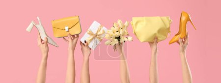 Weibliche Hände mit einem Strauß Tulpen, Handtaschen und Stöckelschuhen auf rosa Hintergrund. Einkaufen zum Internationalen Frauentag