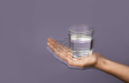 Photo for Trembling hand with glass of water on color background. Parkinson's Awareness Month - Royalty Free Image
