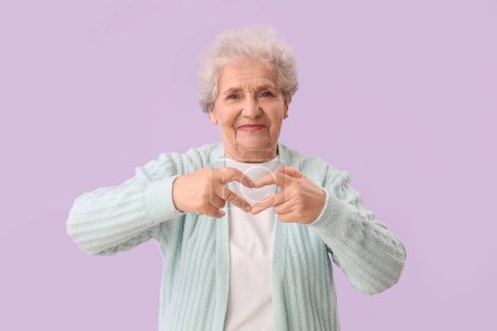 Femme âgée faisant c?ur avec ses mains sur fond lilas
