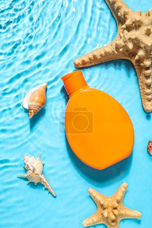 Crème solaire avec étoiles de mer et coquillages dans l'eau sur fond de couleur