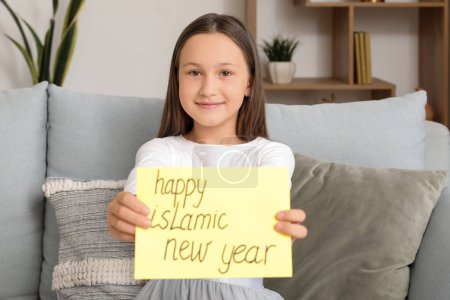 Little Muslim girl with greeting card for Islamic New Year at home