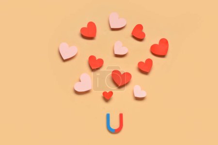 Magnet with paper hearts on orange background. Love concept