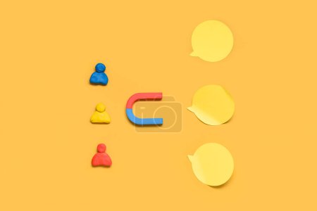 Magnet with group of customers and sticky notes on yellow background. Marketing concept