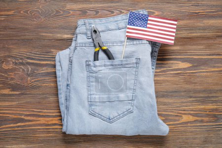 Pantalones vaqueros con bandera de USA y alicates sobre fondo de madera. Fiesta del Día del Trabajo
