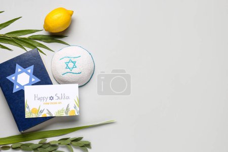 Sukkot festival composition with four species (lulav, hadas, arava, etrog), Torah and greeting card on grey background