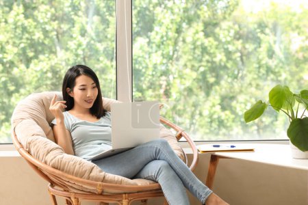 Beautiful Asian woman with laptop learning English language online at home