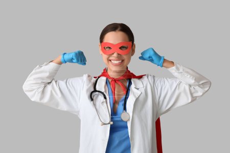 Schöne Ärztin im Superheldenkostüm zeigt Muskeln auf weißem Hintergrund