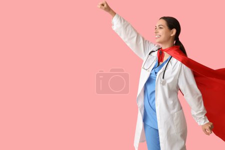 Hermosa doctora en traje de superhéroe sobre fondo rosa