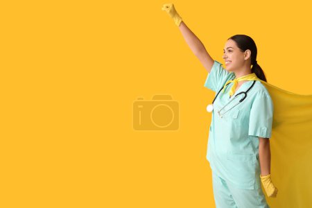 Beautiful female doctor in superhero costume on yellow background