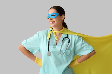Jeune femme médecin en costume de super-héros sur fond blanc