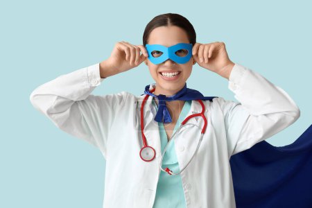 Jeune femme médecin en costume de super-héros sur fond bleu