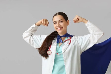 Belle femme médecin en costume de super-héros montrant les muscles sur fond blanc