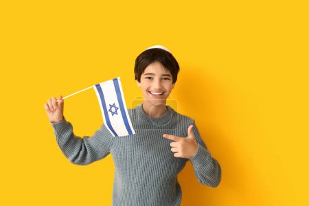 Little boy in kipa pointing at Israel flag on yellow background