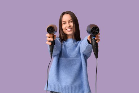 Photo for Happy young woman with hair dryers on lilac background - Royalty Free Image