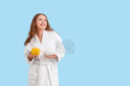 Photo for Young woman in bathrobe with loofahs on blue background - Royalty Free Image
