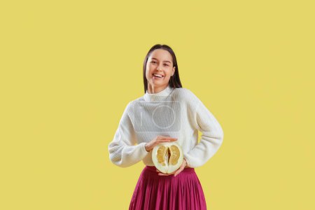 Foto de Mujer joven sonriente con medio pomelo sobre fondo amarillo - Imagen libre de derechos