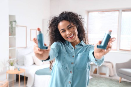Sourire jeune femme afro-américaine avec inhalateurs d'asthme dans la chambre