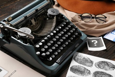 Máquina de escribir retro, huellas dactilares y ropa en mesa de madera