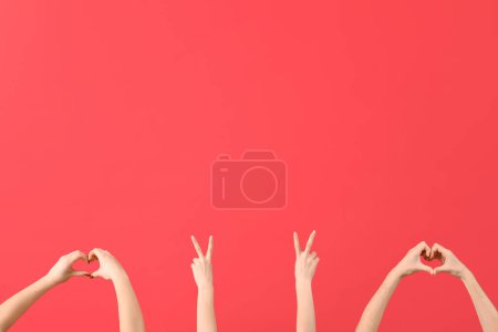 Foto de Manos femeninas mostrando paz y gestos de corazón sobre fondo rojo - Imagen libre de derechos