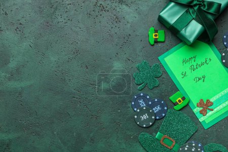 Composición con fichas de póquer, tarjeta de felicitación y decoraciones para la celebración del Día de San Patricio sobre fondo grunge verde