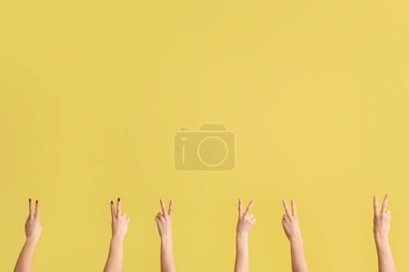 Téléchargez les photos : Mains féminines montrant des gestes de paix sur fond jaune - en image libre de droit