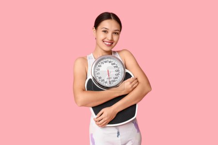 Photo for Young woman in sportswear and with weight scales on pink background. Slimming concept - Royalty Free Image