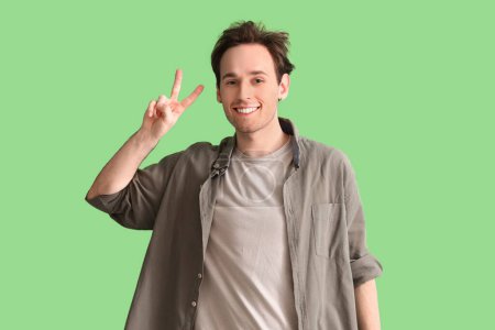 Téléchargez les photos : Jeune homme montrant deux doigts sur fond vert - en image libre de droit