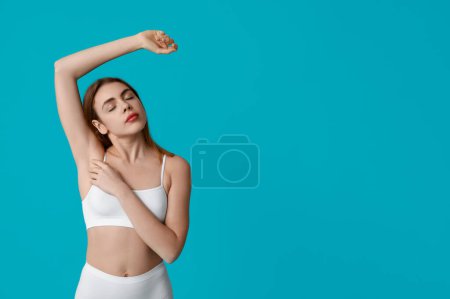 Beautiful young woman after depilation of armpit on turquoise background