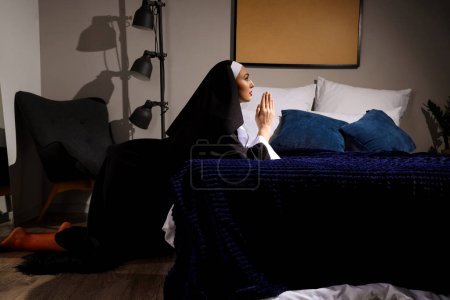 Sexy monja rezando en el dormitorio
