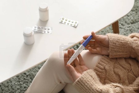 Photo for Woman with pregnancy test and pills on table at home, closeup - Royalty Free Image