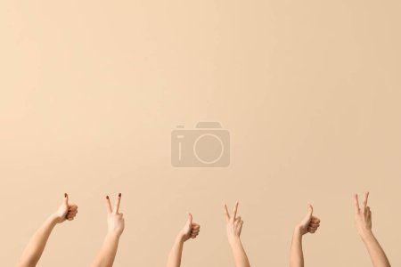 Foto de Manos femeninas mostrando paz y gestos de pulgar hacia arriba sobre fondo beige - Imagen libre de derechos
