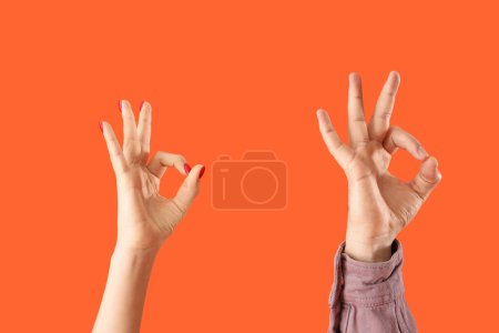 Téléchargez les photos : Personnes montrant OK sur fond orange - en image libre de droit