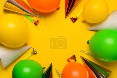 Festliche Luftballons, Krachmacher und Partyhüte auf gelbem Hintergrund