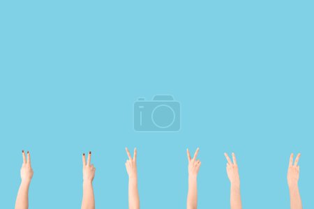 Téléchargez les photos : Mains féminines montrant des gestes de paix sur fond bleu - en image libre de droit