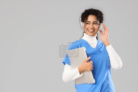 Stagiaire médicale afro-américaine féminine dans un casque avec ordinateur portable sur fond clair