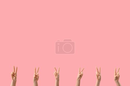 Téléchargez les photos : Mains féminines montrant des gestes de paix sur fond rose - en image libre de droit