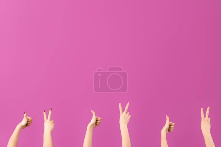 Téléchargez les photos : Mains féminines montrant la paix et les gestes du pouce sur fond violet - en image libre de droit